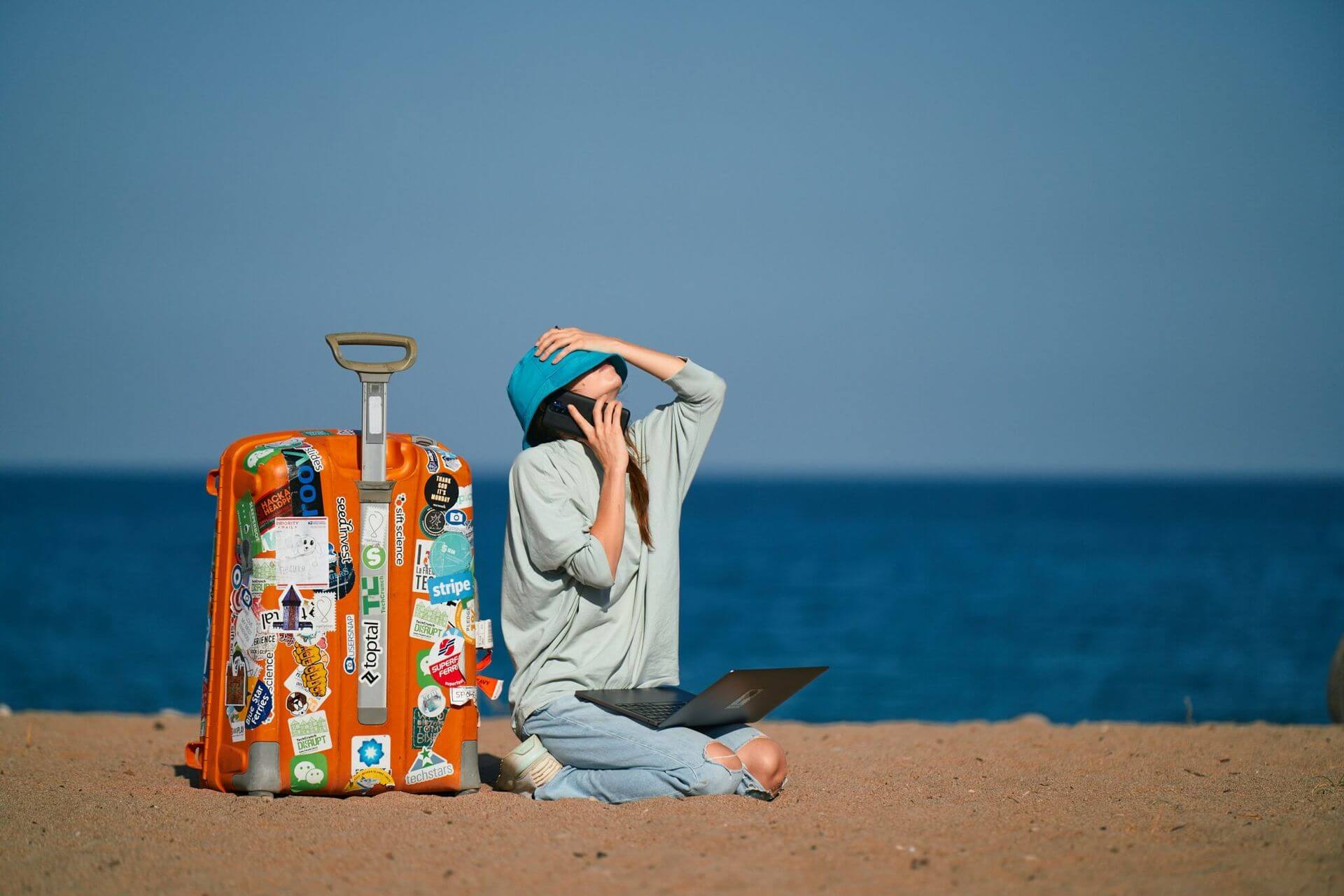corporate travel: woman on beach with suitcase and laptop